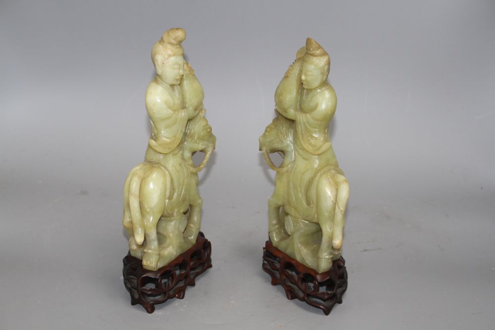 A pair of Chinese bowenite jade groups of a lady riding a horse, wood stands total height 26.5 and 27cm